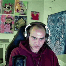 a bald man wearing headphones is sitting in front of a microphone .