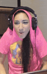 a woman wearing headphones and a pink shirt that says ' l.a. ' on it