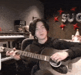 a man is playing an acoustic guitar in front of a sign that says aque