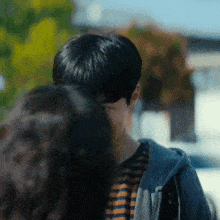 a man in a striped shirt is standing next to a woman in a hoodie .