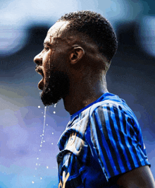 a man in a blue and black striped shirt is sweating and spitting water