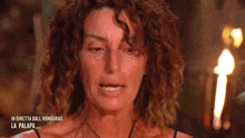 a woman with curly hair is crying in front of a torch .