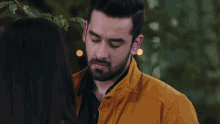 a man in a yellow jacket looks down at a woman