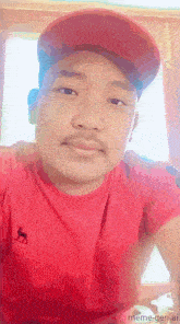 a man wearing a red shirt and a red hat is taking a selfie