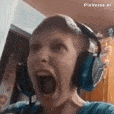 a boy wearing headphones is screaming with his mouth open .