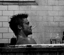 a man smoking a cigarette while taking a bath in a bathtub filled with bottles