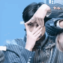 a man in a striped suit covering his face with his hands
