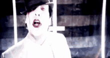 marilyn manson is wearing a top hat and a white shirt .