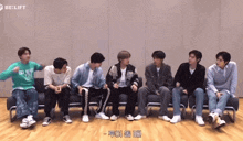 a group of young men are sitting on a couch and one of them is wearing a green sweater that says kid who loves you