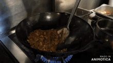 a wok is being stirred on a stove with the words made in animotica above it