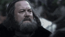 a man with long hair and a beard is looking down