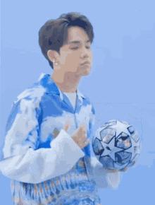 a man in a blue shirt is holding a soccer ball in his hands