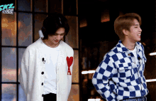 two men are standing next to each other and one has a heart on his sweater