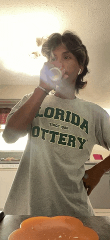 a man wearing a florida lottery t-shirt drinks from a cup