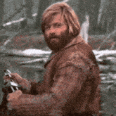 a man with a beard and long hair is holding a sword in his hand .