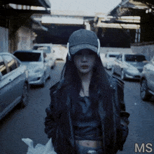 a woman wearing a hat and headphones is standing on a street with the letters ms below her