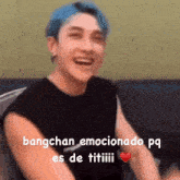 a man with blue hair and a black shirt is laughing and holding a heart .
