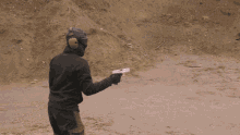 a man wearing a mask is holding a gun in front of a suv