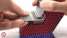 a person is holding a credit card in front of a stack of red and blue beads