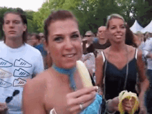 a woman wearing a blue scarf is eating a banana in a crowd