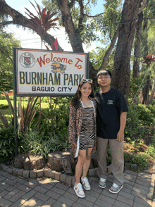 two people stand in front of a sign that says burnham park baguio city