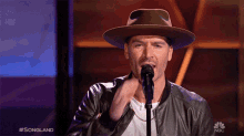 a man singing into a microphone with the nbc logo in the corner