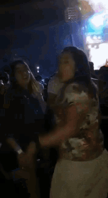 a group of people are dancing in a dark room with a blue light behind them