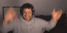 a man wearing headphones is raising his arms in the air in a room .