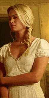 a woman in a white dress has a braided hairstyle