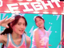 two girls are dancing in front of a sign that says " fight "