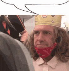 a man with long hair and a crown on his head is wearing a red bandana .