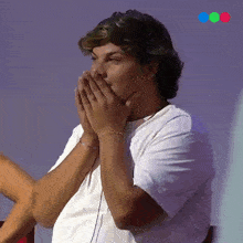 a man in a white shirt is covering his mouth