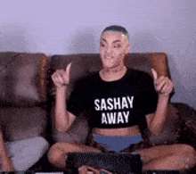 a man is sitting on a couch wearing a sashay away t-shirt and underwear .