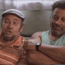 two men are sitting next to each other with their arms crossed and one has a watch on his wrist