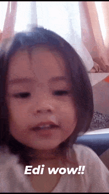 a little girl is making a surprised face and says edi wow !