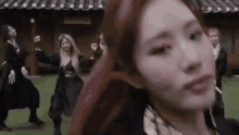 a group of women are dancing in front of a building while a woman looks at the camera .
