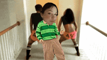 a girl in a green and blue striped shirt is dancing with two other girls