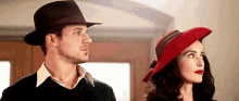 a man in a hat and a woman in a red hat are standing next to each other in a room .