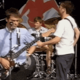 a man is playing a guitar in front of a drum set