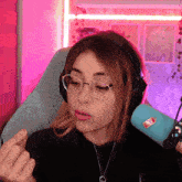 a woman wearing glasses and headphones stands in front of a microphone with a sticker on it that says soda