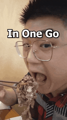 a man with glasses is eating a piece of meat with the words in one go below him