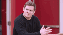 a man in a black sweater leans on a railing with his hands folded