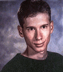 a young man in a green shirt is posing for a picture in front of a cloudy sky .