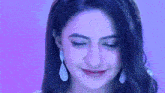 a close up of a woman 's face with a purple background and earrings .