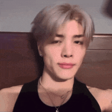 a man wearing a black tank top and a necklace is making a funny face