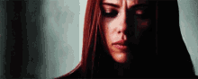 a close up of a woman 's face with red hair and a tear running down her cheek .