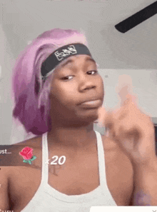 a man with pink hair and a headband on his head is giving the middle finger .