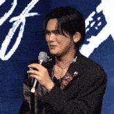 a man is holding a microphone in front of a blue background
