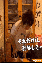 a man in a puma shirt stands in front of a cabinet with chinese writing on it