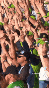 a crowd of people are raising their hands in the air at a stadium .